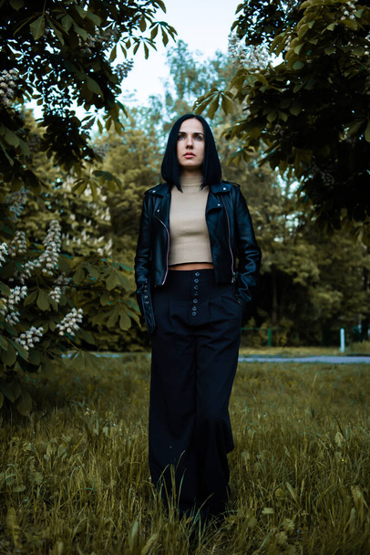 giovane bella donna in un abito nero e una giacca su una passeggiata nel parco - Foto, immagini