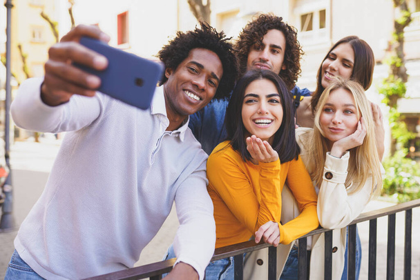Black man with afro hair taking a smartphone selfie with his multi-ethnic group of friends. - Valokuva, kuva
