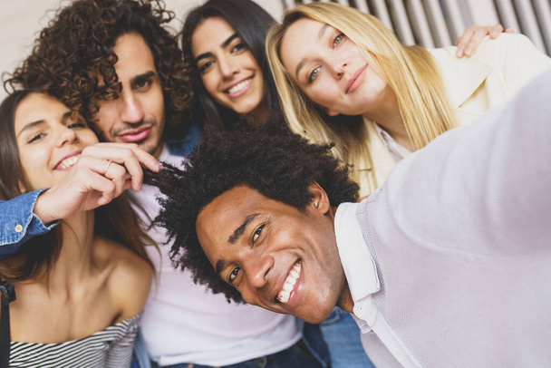 Grupo multiétnico de amigos tomando una selfie juntos mientras se divierten al aire libre. - Foto, imagen