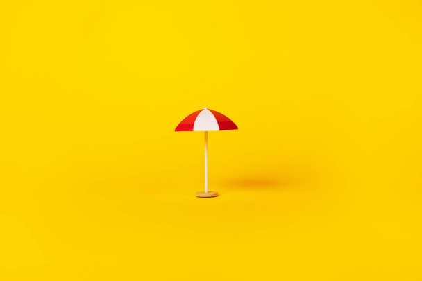 Sarı zemin üzerinde kırmızı ve beyaz plaj şemsiyesi, yaz ve tatil konsepti - Fotoğraf, Görsel