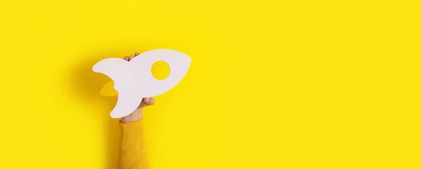 rocket in hand over yellow background, panoramic layout - Photo, Image