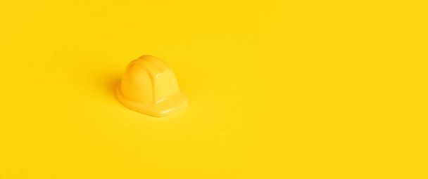 Keltainen lelu työntekijän kypärä keltaisella taustalla, minimalismin rakennuskonsepti, panoraama kuva - Valokuva, kuva