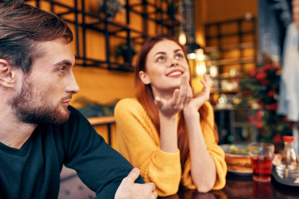homem e mulher estão sentados em um café na mesa e gesticulando com as mãos amigos emoções divertido interior - Foto, Imagem