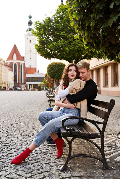 Beautiful young couple cuddling on a bench in a European town. Romatnic date and love concept. - Foto, Imagem