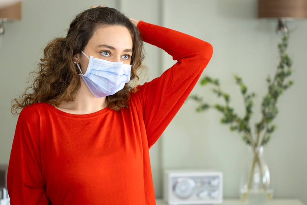 Young woman wearing a mask to protect herself against the coronavirus at home - Photo, image