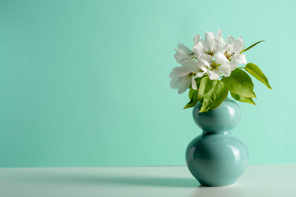 fruit tree pear flowers in a turquoise jar on white table. Copy space - Foto, afbeelding