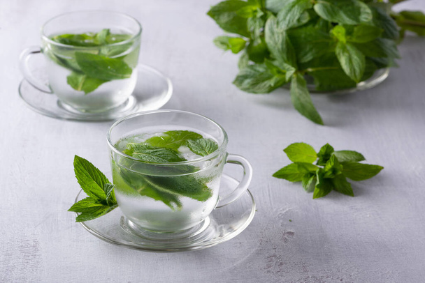 Buzlu nane çayı, ferahlatıcı bitkisel içecek buzlu ve koyu arkaplanda taze yapraklar. - Fotoğraf, Görsel