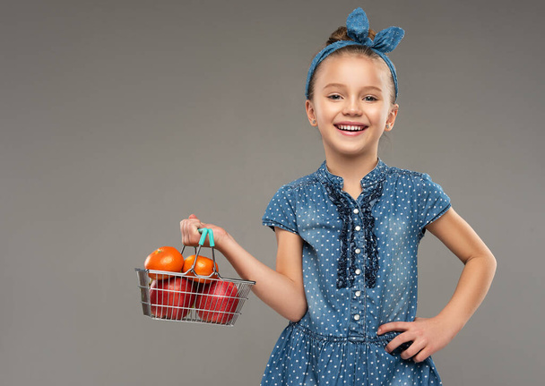 Nevető kislány egy játékkosárral a kezében. Gyermek áruk és termékek. - Fotó, kép