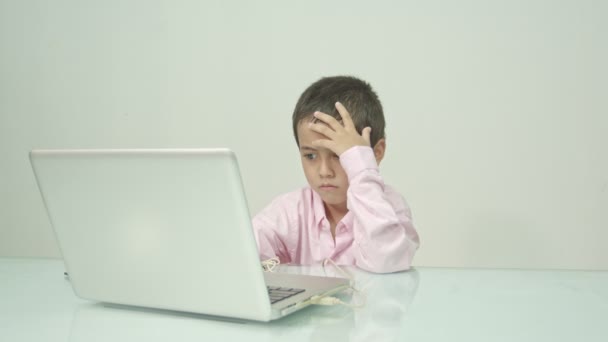 Chlapec v růžové košili si užíval sledování šťastného laptopu.Studio portrét, koncept s bílým pozadím.  - Záběry, video