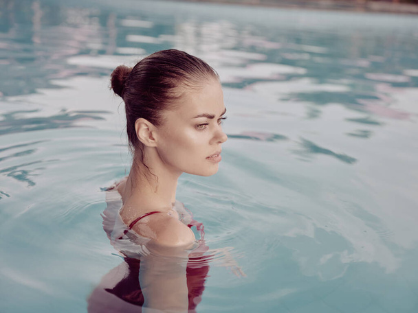όμορφη γυναίκα με μακιγιάζ στο πρόσωπό της κολυμπά στην πισίνα πολυτελείς διακοπές - Φωτογραφία, εικόνα