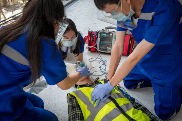 Spoedeisende medische teams helpen bewusteloze patiënten door het gebruik van geautomatiseerde externe defibrillatoren (AED) en het verstrekken van zuurstof. Tijdens de redding van bewusteloze arbeiders. Selectie van focuspunten. - Foto, afbeelding