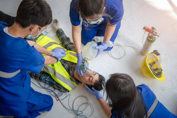 Notarztteams helfen bewusstlosen Patienten, indem sie automatische externe Defibrillatoren (AED) einsetzen und Sauerstoff zur Verfügung stellen. Während der Rettung bewusstloser Arbeiter auf der Baustelle - Foto, Bild