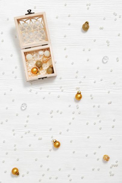 Christmas background with golden small balls in wooden box on white wood. Beautiful New Year and Winter Holiday concept. Flat lay. Top view. - Foto, Imagen