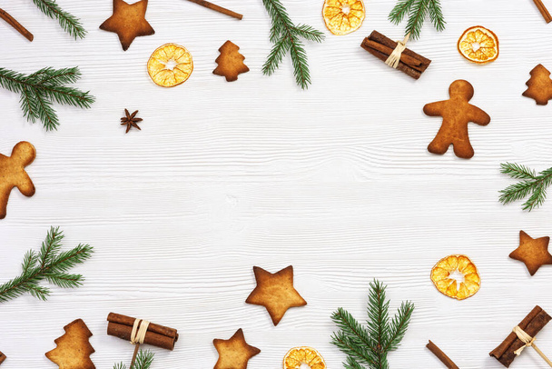 Christmas cookies assorted top view, green fir branches, cinnamon sticks, dry oranges on white wooden background, flat lay. New Year sweet food. - Zdjęcie, obraz