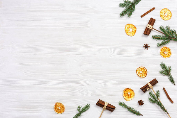 Winter or Christmas fragrance, spices, cinnamon, dry orange slices, anise star, pine branches on white wooden background with copy space. Flat lay, top view. - Foto, imagen