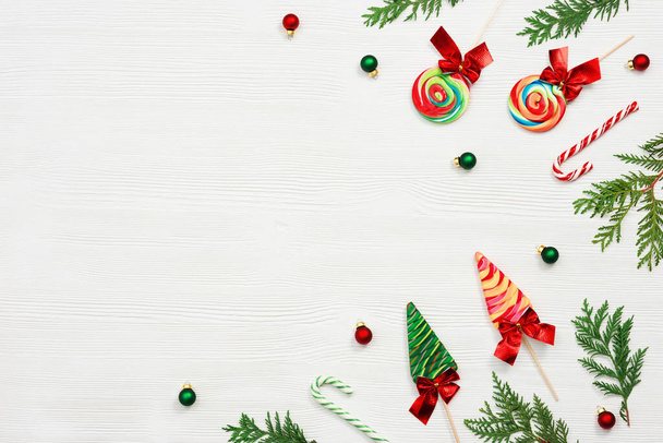 Colorful Christmas swirl candy, traditional New Year candy canes, xmas sweet food and New Year small balls on white wooden background. Flat lay, Top view. - Φωτογραφία, εικόνα