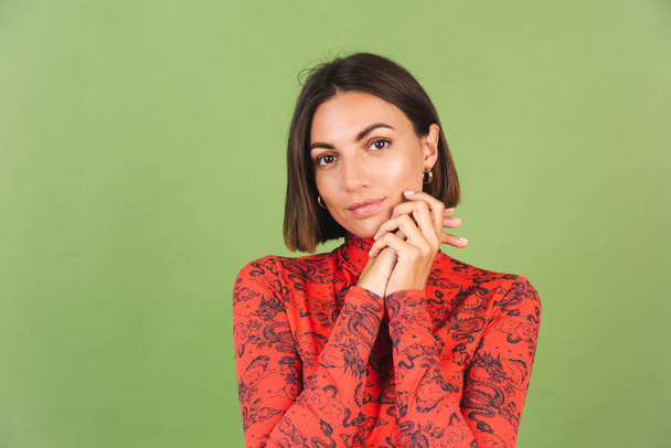 Pretty short hair woman with light make up golden earrings red china dragon printed blouse on green background, positive emotions, confident smile - Photo, Image
