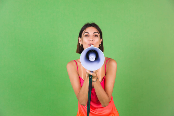 Stylish woman in pink silk dress on green background, happy excited joyful cheerful shouting in megaphone, isolated - Photo, Image