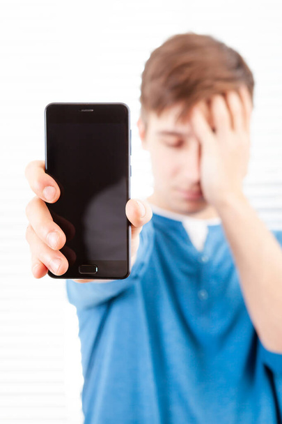 Sad Young Man show a Screen of Mobile Phone in a Room - Φωτογραφία, εικόνα