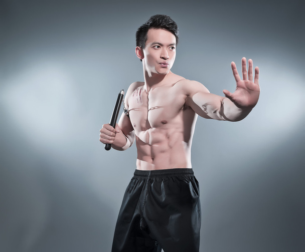 muskulöser asiatischer Kung-Fu-Mann in Action-Pose mit Nunchucks. Blut s - Foto, Bild