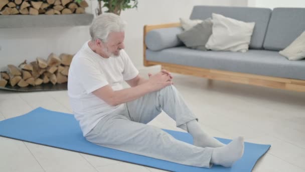 Anciano mayor teniendo dolor de rodilla en esterilla de yoga en casa - Metraje, vídeo