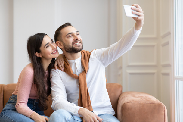 Couple arabe joyeux faisant Selfie sur téléphone portable à la maison - Photo, image