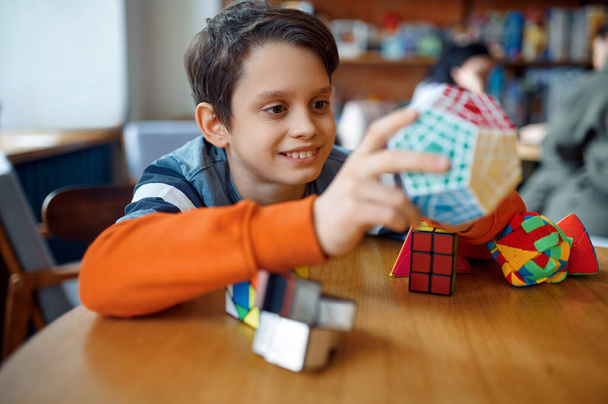 Smiling little boy play with colorful puzzle cubes. Toy for brain and logical mind training, creative game, solving of complex problems - Foto, afbeelding