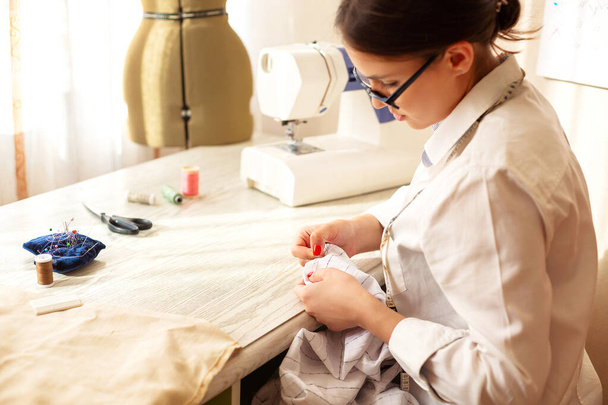 Oldalnézet tehetséges női tervező létrehozása ruházat, miközben dolgozik a próbababa műteremben - Fotó, kép