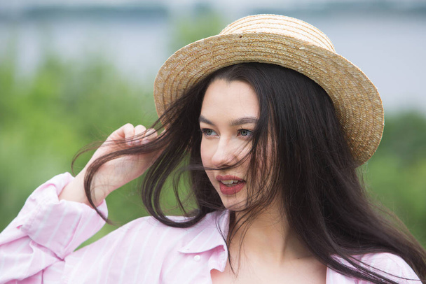 Портрет молодої красивої дівчини в капелюсі солом'яного човна. Вітряна погода в літній сонячний день
. - Фото, зображення