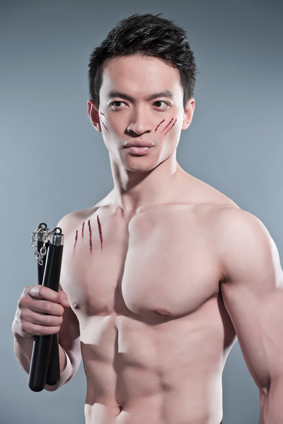 izmos ázsiai kung fu ember nunchucks. vér karcolások az ő - Fotó, kép