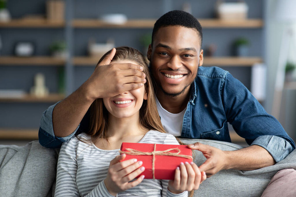Sevgi dolu siyahi erkek arkadaşı evde romantik hediyelerle sevgilisine sürpriz yapıyor. - Fotoğraf, Görsel