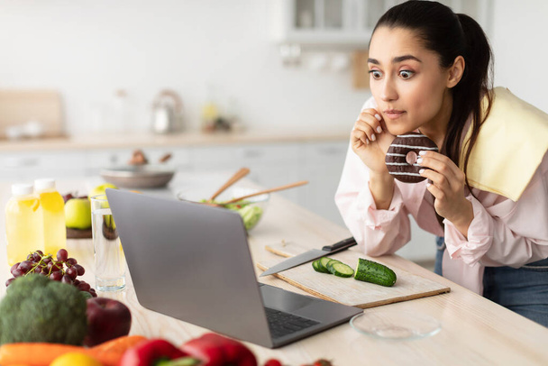 Yllättynyt järkyttynyt nainen katsomassa elokuvaa kannettavan tietokoneen syöminen makea välipala - Valokuva, kuva