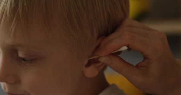 Vrouwenhand reinigt het oor van een kleine blonde jongen. Kinderhygiëne. close-up. Natuurlijk daglicht - Video
