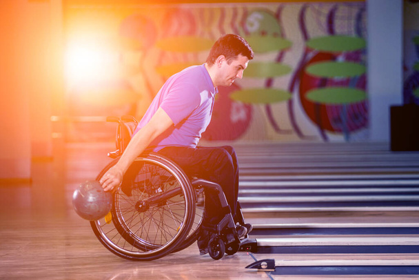 Young disabled man in wheelchair playing bowling in the club - Zdjęcie, obraz