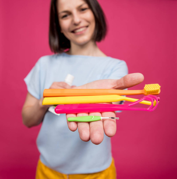 Beautiful young woman uses an oral care kit consisting of a tongue scraper, single tufted and interdental brush - Φωτογραφία, εικόνα