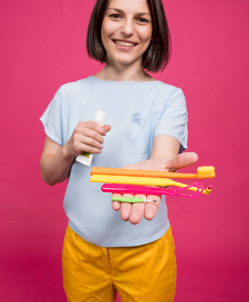 Beautiful young woman uses an oral care kit consisting of a tongue scraper, single tufted and interdental brush - Foto, imagen