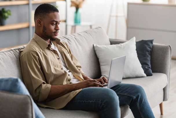 Serious Black Man Using Laptop Browsing Internet Sitting At Home - Photo, Image