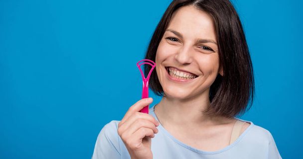 Beautiful happy young woman using interdental brush on blue background - 写真・画像