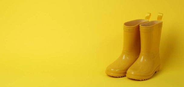 Μπότες από καουτσούκ για κηπουρική σε κίτρινο φόντο - Φωτογραφία, εικόνα