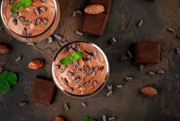 Veganistische chocolademousse met munt, reep chocolade en cacaobonen op een donkere achtergrond. Kopieerruimte - Foto, afbeelding
