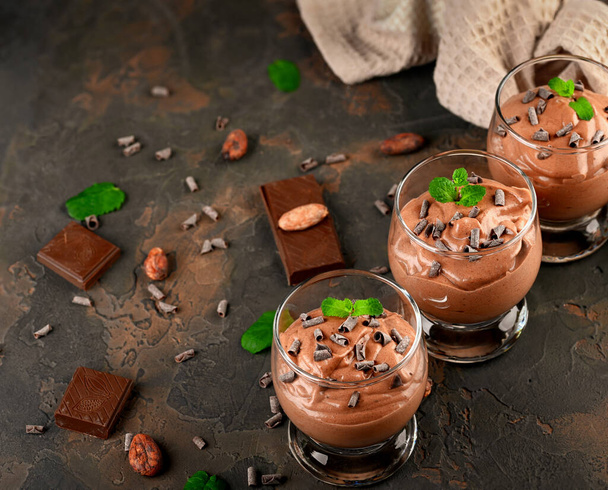 Веганський шоколадний мус з м'ятою, батончиком шоколаду та какао-бобами на темному тлі. Копіювати простір
 - Фото, зображення