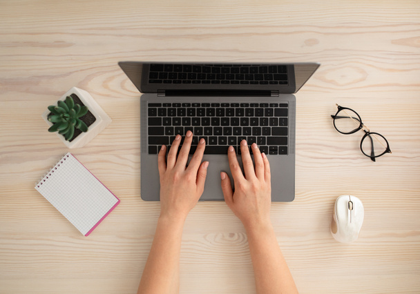 Koncepcja miejsca pracy. Kobiece ręce pracujące na pulpicie biurowym, pisanie na klawiaturze laptopa, widok z góry - Zdjęcie, obraz