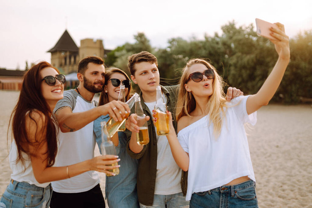 Group of people doing selfie with phone at the beach. Young friends enjoy summer party together. People, lifestyle, travel, nature and vacations concept. - Foto, afbeelding