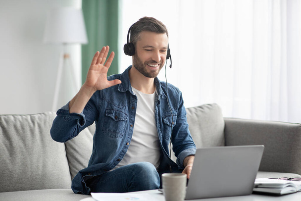 Sorrindo homem tendo videoconferência de negócios, usando fone de ouvido e laptop - Foto, Imagem