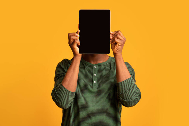 смішний афроамериканський чоловік покриває обличчя цифровим планшетом з чорним екраном
 - Фото, зображення
