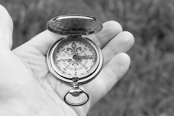 Stary klasyczny kompas nawigacyjny w ręku na naturalnym tle jako symbol turystyki z kompasem, podróży z kompasem i zajęć na świeżym powietrzu z kompasem - Zdjęcie, obraz