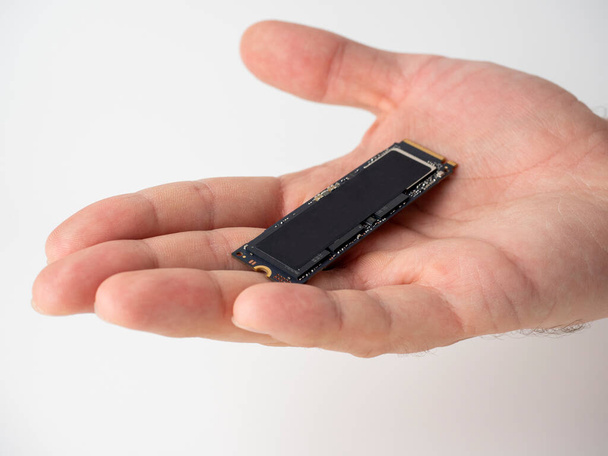 auf der männlichen Handfläche befindet sich eine SSD-Scheibe im m2-Format. Neue Technologien zur Speicherung und schnellen Datenübertragung. Upgrade für digitale Geräte - Foto, Bild