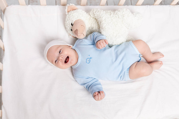 happy baby boy in crib with teddy bear toy, children and birth concept - Foto, Imagem