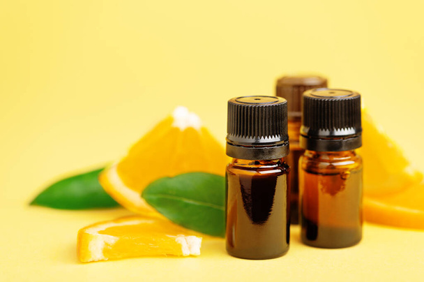 Flaschen mit ätherischem Zitrusöl mit Orangenscheiben auf gelbem Hintergrund. Nützliche Aromatherapie, aromatische Bäder, alternative Medizin, Vitamine. Schönheit Naturprodukt - Foto, Bild