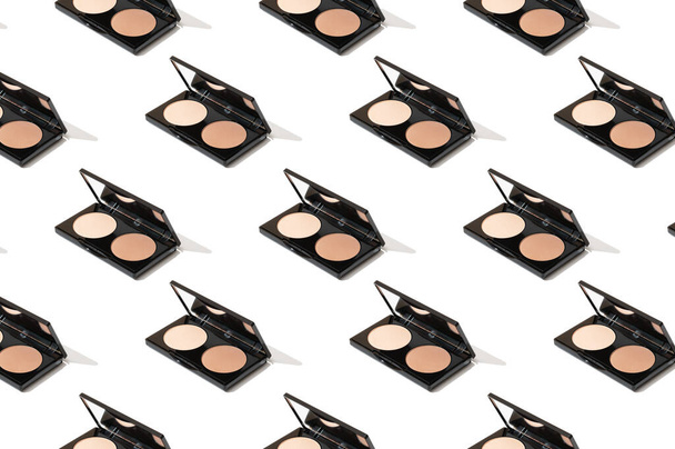 Black compact palette with foundation, powder, bronzer, open with a mirror. Applying a makeup tone for a professional makeup artist. Bright pattern of beauty products on a white background. - Φωτογραφία, εικόνα